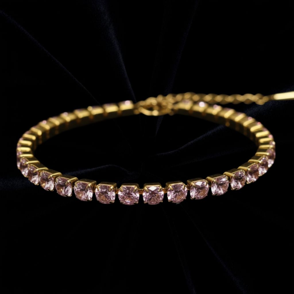 Guld armband med rosa stenar på svart sammetstyg i bakgrunden